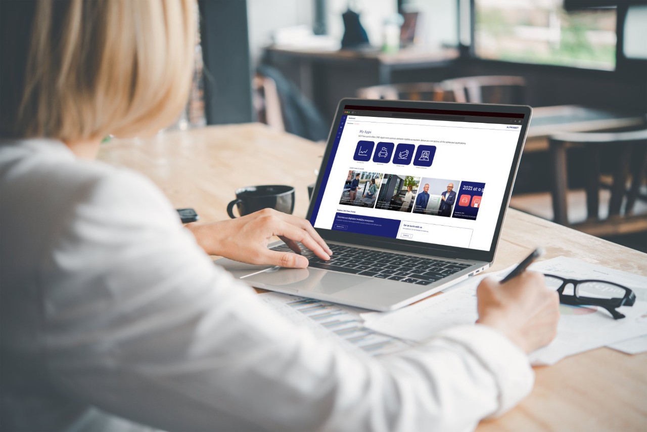 Person using a laptop at a desk in a modern office, interacting with the Alphabet digital platform displayed on the screen.