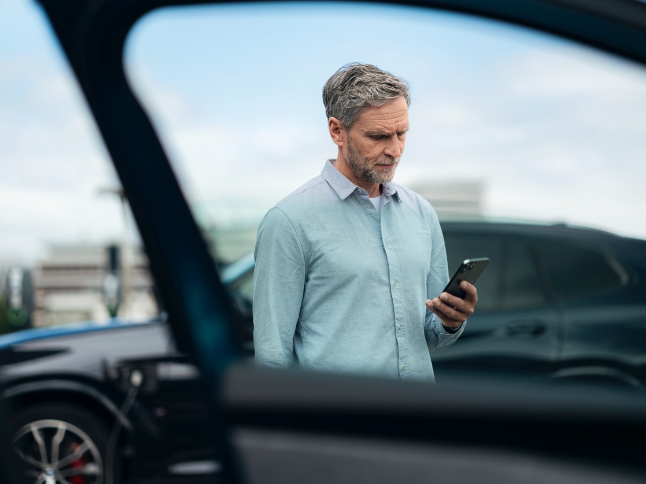 Man in a light blue shirt holding a smartphone.