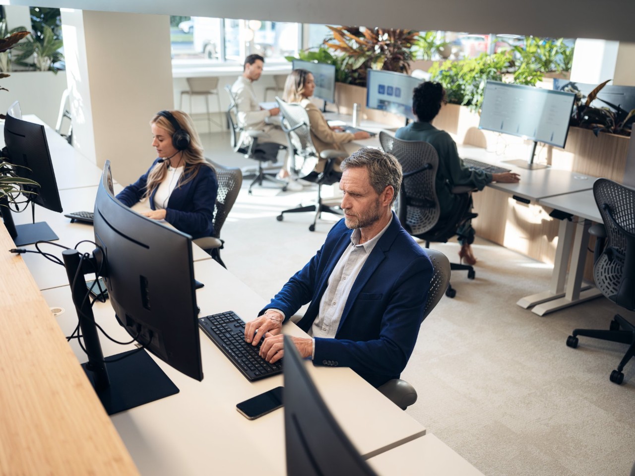 Man in blue suit in front of a computer monitor.